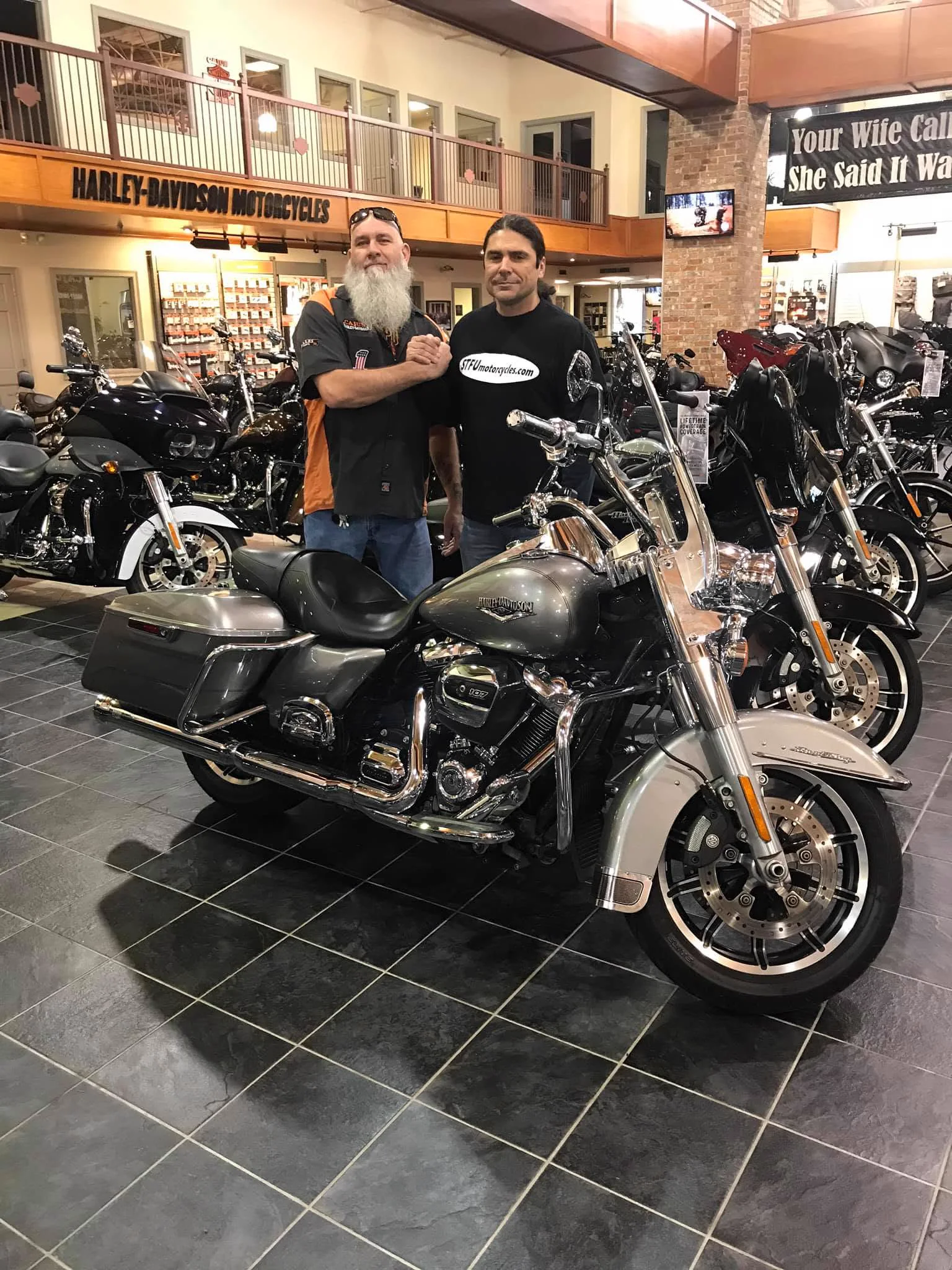 Scott standing in a Harley-Davidson showroom beside the used silver Road King that became Dragbag
