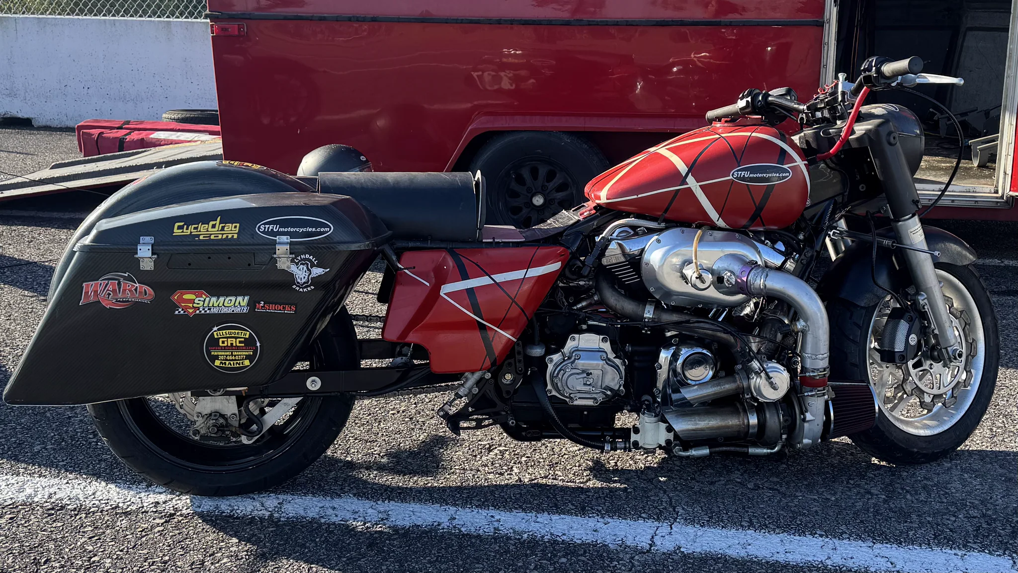 Close side view of Eddie's red Eddie Van Halen tribute paint, carbon-fiber saddlebags, turbo system, and STFU Motorcycles decals beside the red race trailer