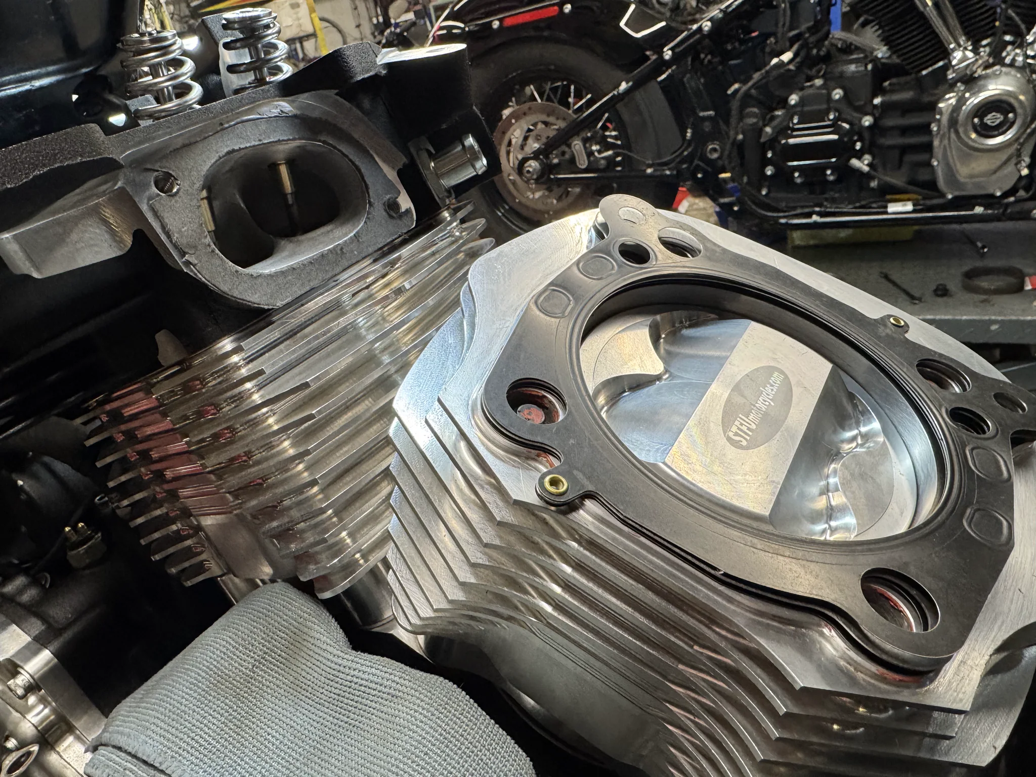 Close-up of disassembled race engine heads, valves, pistons, and machined STFU Motorcycles parts on Scott's workbench